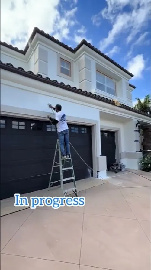 Exterior Painting by Brush & Beyond Paint in San Juan Capistrano, CA. Spraying trim above the garage on a tile roof Spanish home.